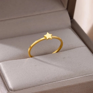 Macro detail of minimalist gold star ring on a premium gray silk jewelry display box