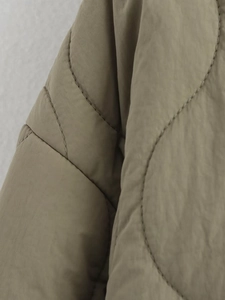 Detailed close-up of khaki quilted jacket featuring wavy stitching and micro-wrinkle texture