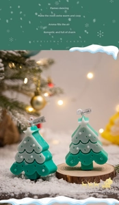 Detail shot of a mint green Christmas tree candle with snow accents and star topper