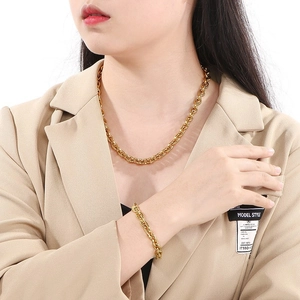 Ensemble collier et bracelet en maille dorée porté par un mannequin en veste