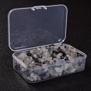 Detailed macro view of black rutilated quartz crystal chips in a clear storage box