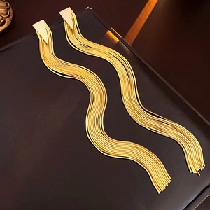Detail of gold-plated triangle stud earrings featuring long metal snake chain tassels