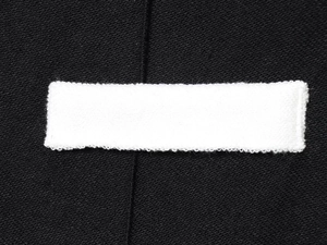Détail du tissu en tweed noir texturé avec un empiècement rectangulaire blanc cousu
