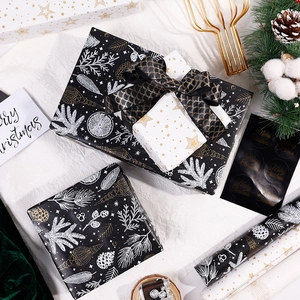 Elegant black and gold Christmas gift wrapping set with paper rolls, boxes, and stickers