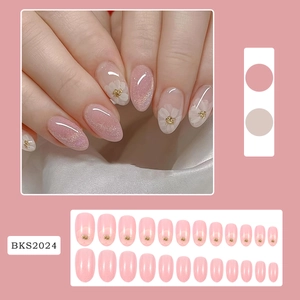 Detail of pink and white flower press-on nails with gold accents and glitter in oval shape