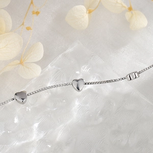 Elegant silver box chain bracelet with heart pendant on a frosted decorative background