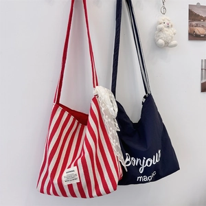 Detail of red-white striped canvas tote and navy blue shoulder bag with Bonjour text