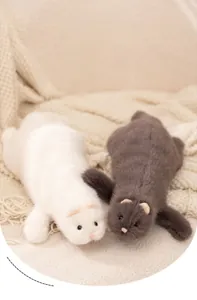 Close-up of realistic white and brown ferret plush toys on a soft knitted blanket