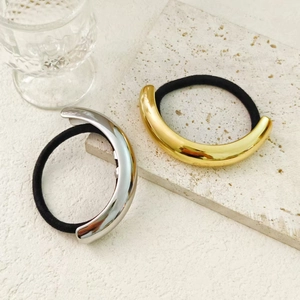 Close-up of gold and silver minimalist metal hair ties on premium stone background