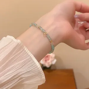 Elegant beaded bracelet with light blue crystals and a gold heart pendant on wrist