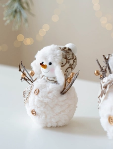 Detailed macro view of plush snowman ornament with golden berries and knit hat details