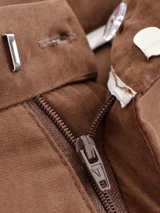 Macro shot of dark brown fabric trousers featuring metal zipper and hook waist closure