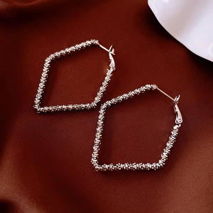 Detailed view of silver geometric diamond-shaped earrings on elegant silk fabric