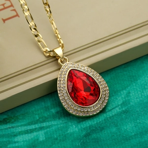 Collar bañado en oro con gota de piedra roja y circonitas sobre una tela verde