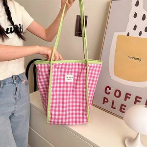 Detail of pink and white checkered tote bag with green straps and branded label