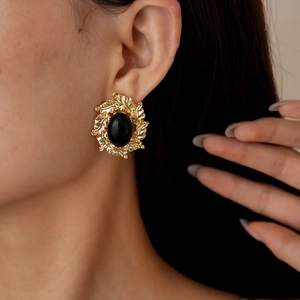 Close-up of vintage gold leaf earrings with oval black stone on a female model