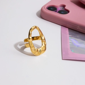 Detailed view of an irregular 18k gold plated stainless steel ring on a white surface