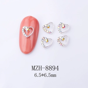 Macro view of 6.5mm heart-shaped nail charms with AB rhinestones on pink manicured nails