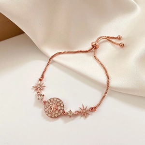 Detail of rose gold adjustable bracelet with sparkling starburst and pavé rhinestone charms