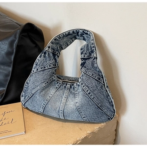 Détail du sac à main en patchwork de denim bleu montrant la texture sur pierre beige