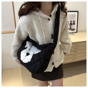 Detail of black quilted crossbody bag featuring a cute white dog embroidery and wide strap