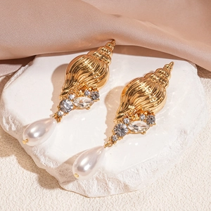 Macro detail of golden conch earrings with sparkling rhinestones and teardrop pearls