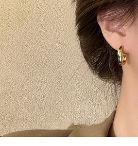 Close-up of minimalist chunky golden C-shaped earring worn on a model's ear