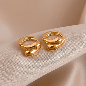 Macro shot of gold layered teardrop earrings on elegant champagne silk background