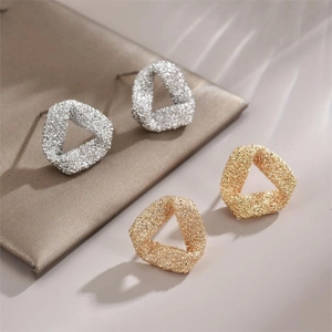 Minimalist matte triangle stud earrings in gold and silver finish set on beige base