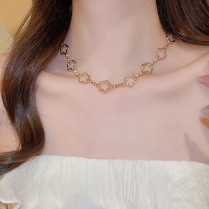 Detail shot of a golden clover necklace worn on the neck with elegant tassel design