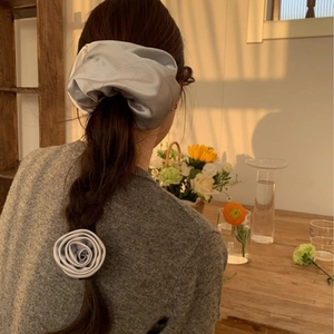 Elegant grey satin scrunchie and rose flower hair tie on braided hair in warm light