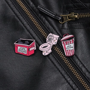 Trois pin's roses en émail avec messages humoristiques sur veste en cuir noir en détail