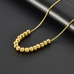 Collier en acier titane plaqué or 18K avec perles polies sur fond en cuir noir élégant