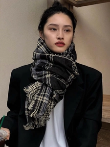 Écharpe à carreaux noir et blanc avec franges portée par un mannequin en blazer noir