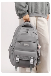 Detail of dark grey backpack featuring tactical buckle pockets and nylon water-resistant fabric