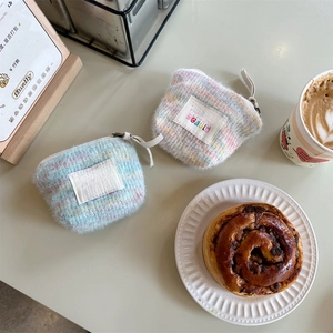 Close-up of rainbow plush mini makeup bags with sozakka beauté label on a cafe table