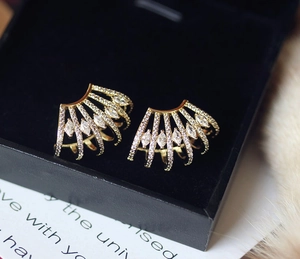 Macro shot of gold fan-shaped stud earrings with sparkling zircon inlay in a jewelry box
