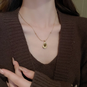 Golden bead chain necklace with tiger eye stone pendant on brown sweater model