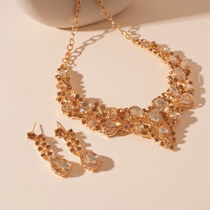 Detail of luxury V-shaped jewelry set featuring teardrop crystals and gold finish