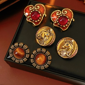 Three pairs of vintage resin heart and unicorn coin earrings on black leather texture