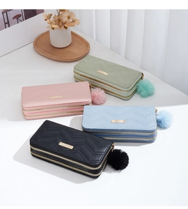 Detail of four colorful long wallets with quilted V-patterns and fluffy pompom charms
