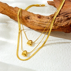Elegante goldene mehrlagige Edelstahlhalskette mit zwei Herzanhängern auf Holzdekor