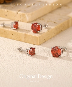 Dettaglio di orecchini a lobo in argento S925 con cristalli rosso-arancio tondi