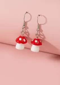 Détail de boucles d'oreilles champignons rouge et blanc au motif dessin animé
