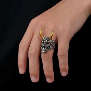 Detail of silver Prajna mask ring with golden horns on model hand against black background