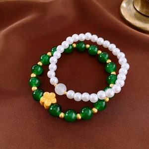 Detail of vintage flower charm bracelets with green beads and imitation pearls on silk