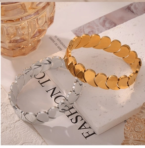 Detail of interlocking leaf-shaped gold and silver bangles on white stone display