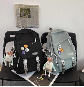 Detailed view of black and sage green nylon backpacks with trendy badges and rabbit charms