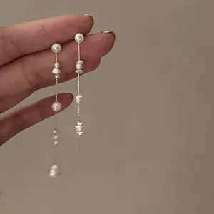 Close-up of elegant gold tassel earrings featuring cascading freshwater baroque pearls
