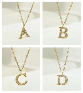 Detailed macro view of four gold zircon necklaces featuring A, B, C, and D letter pendants